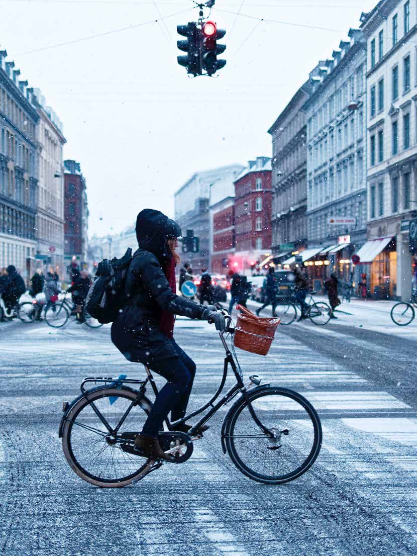 Women riding her bike in snow in Copenhagen.