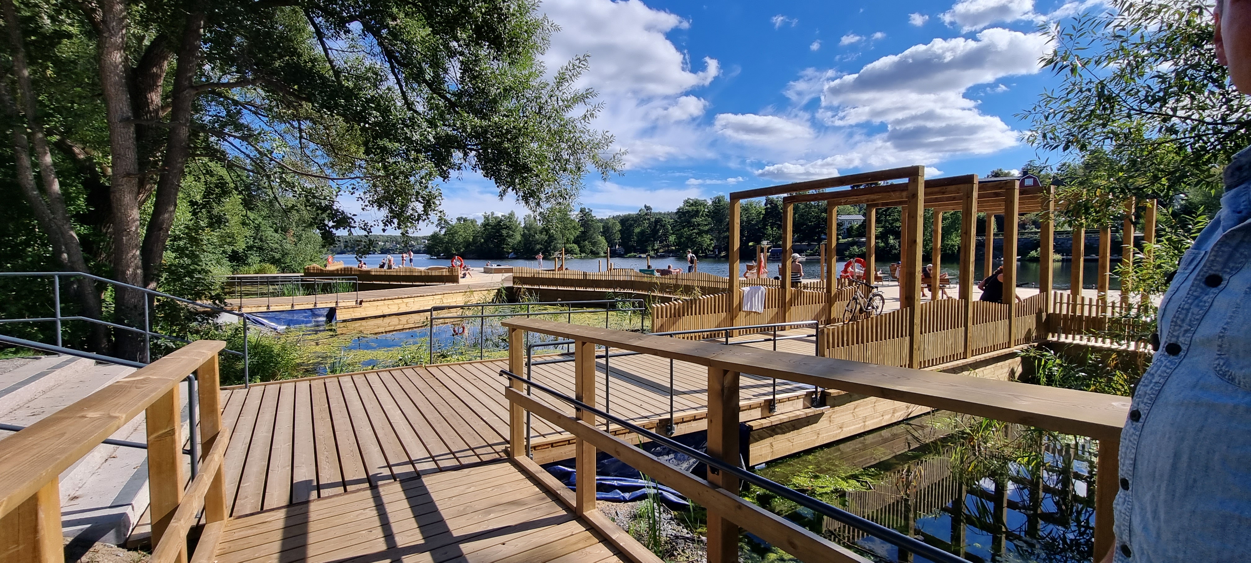 A side photo of Järlasjö sundeck. Wooden deck surrounded by greenery, accessible for pedestrians and cycklist.