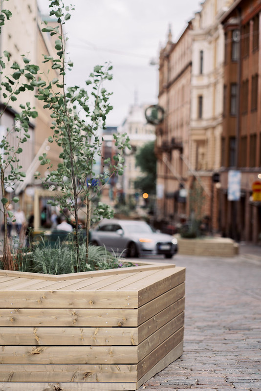 A wooden tree planting box with a seating option for pedestrians.