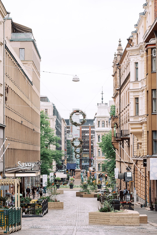 A photo of the summer street where elements of urban greening and street decorations are seen.