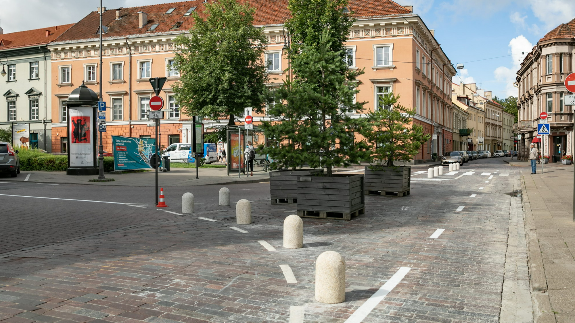 A street view with traffic reduction and diversion elements - such as large tree boxes, signage and bicycle roads.