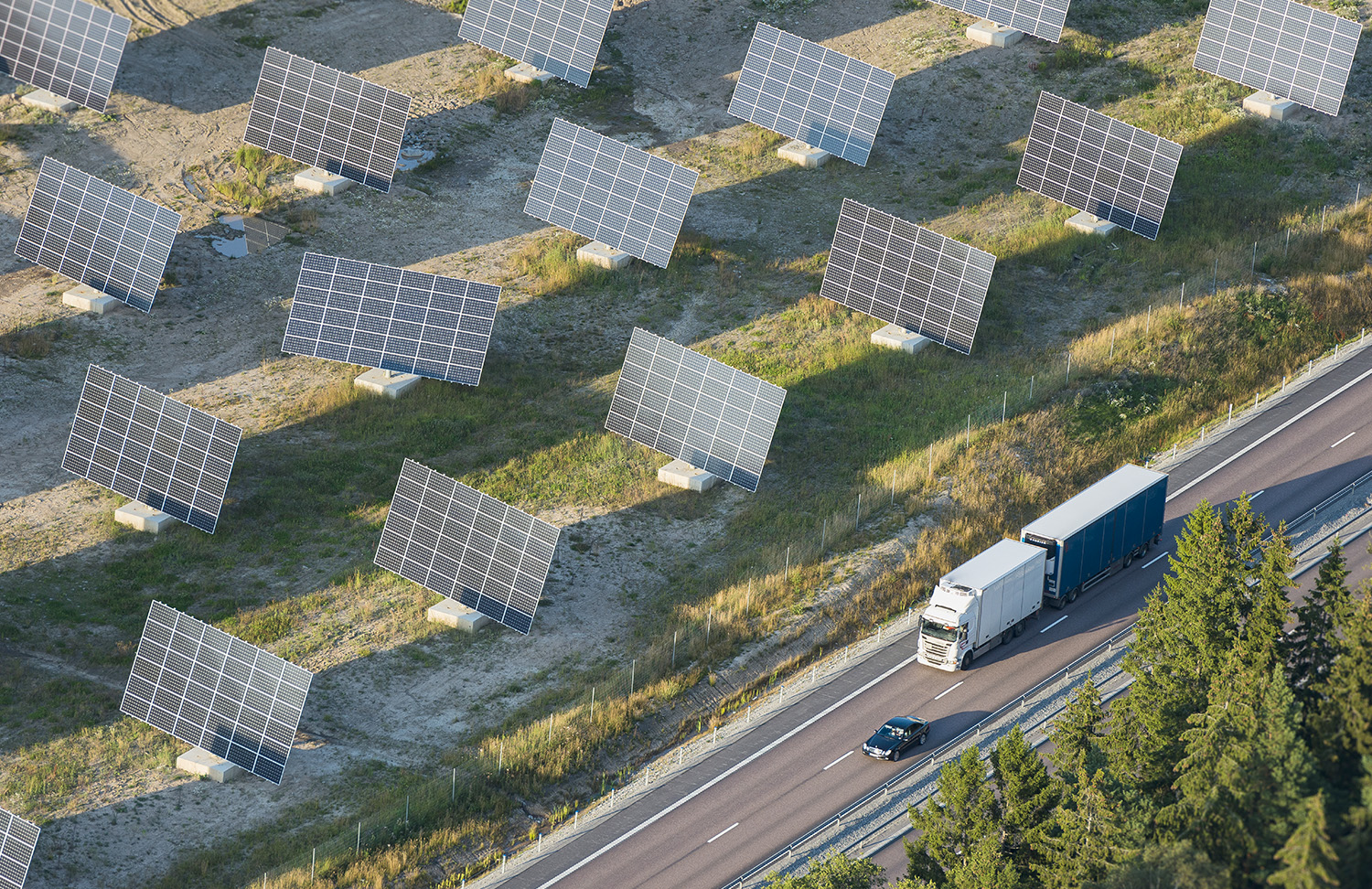Solar panels in field along road with cars
