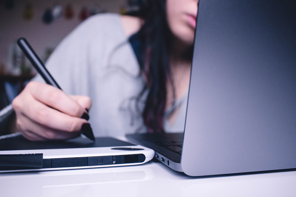 Ung kvinde studerer hjemme ved computern