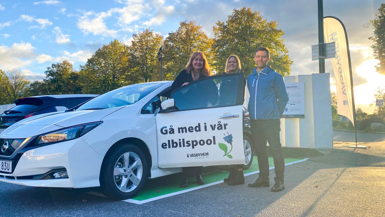 People posing outside electric car