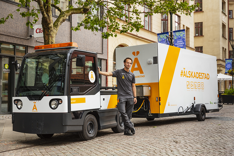 Man standing in front of electric vehicle for picking up waste.