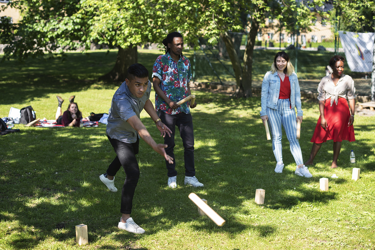 Four youths playing the Swedish lawn game kubb