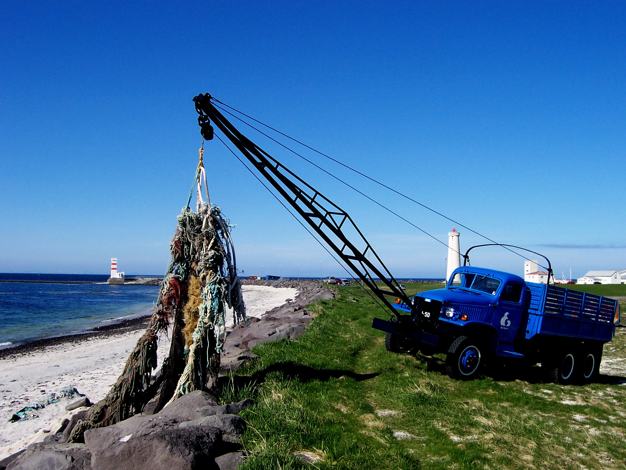 Kranbil som løfter en masse fiskenet på stranden