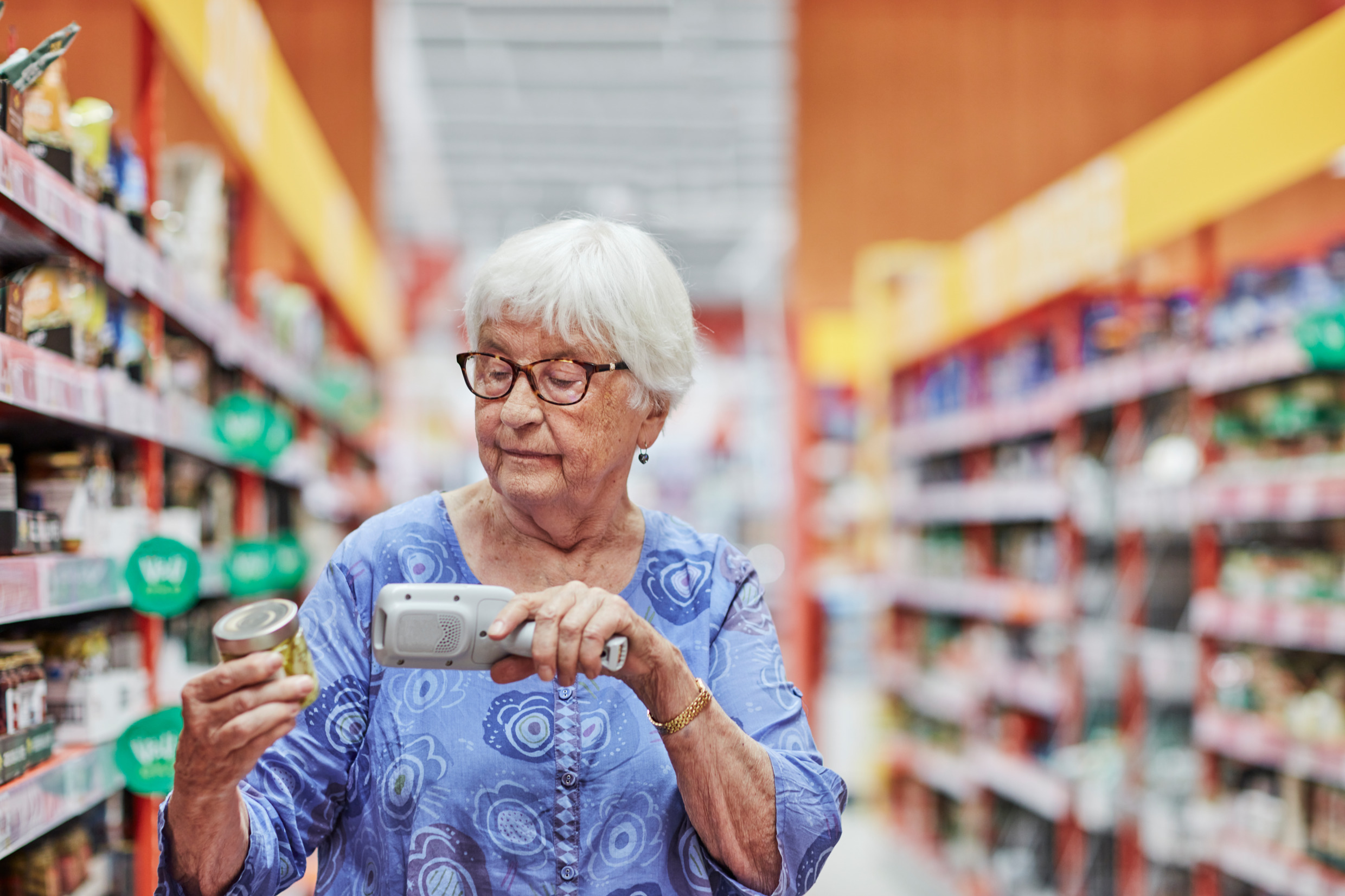 Elder woman scanning product in food store