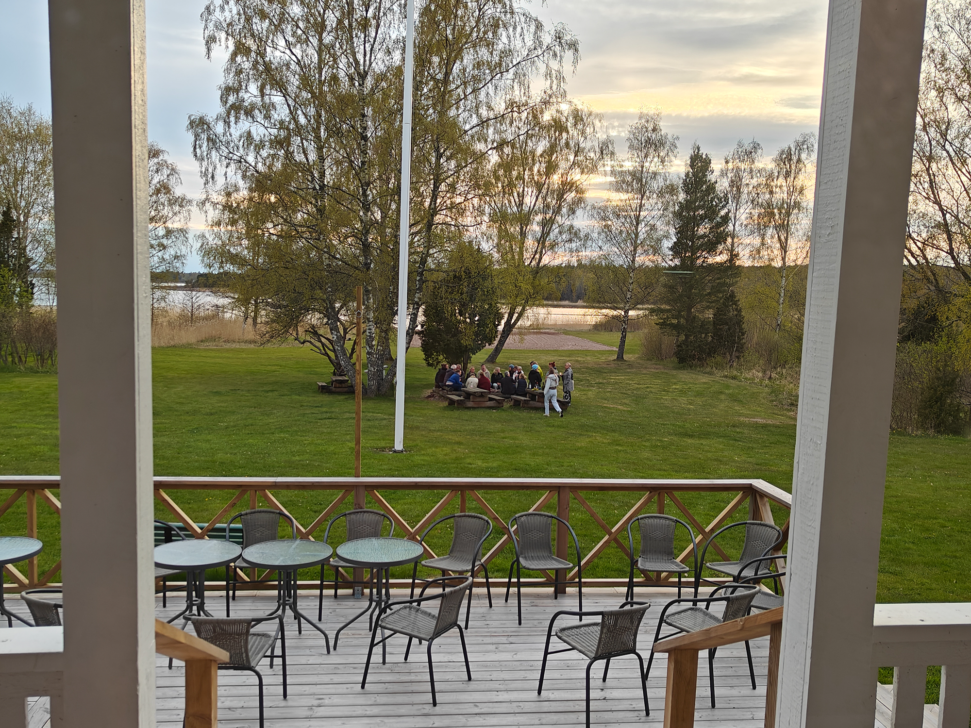 The picture is a doorway looking over a garden where people are sitting together. 